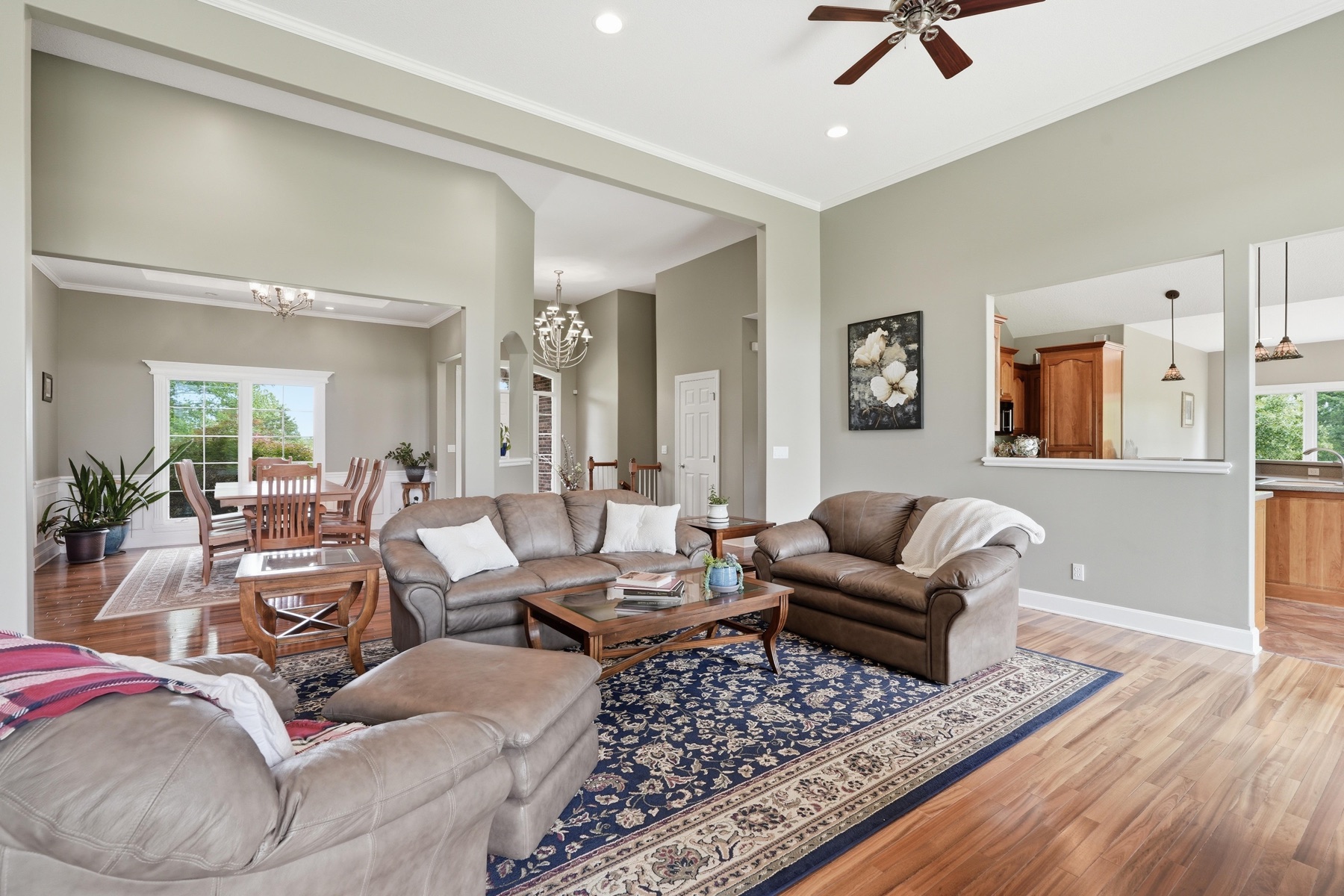 Great room living area of 26619 K-68 Hwy with vaulted ceiling, tan leather sectional seating, a deep blue Persian rug on hardwood floors, and openings into the dining room and kitchen beyond